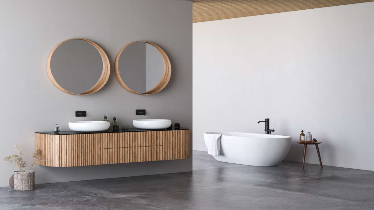 Ruime moderne badkamer met dubbele opbouw wastafels, onderbouw, spiegels, een ruim bad en grijze muren en wanden.
