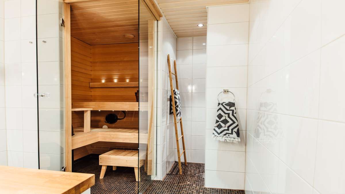 Dit is een traditionele sauna naast een douchecabine in een badkamer.