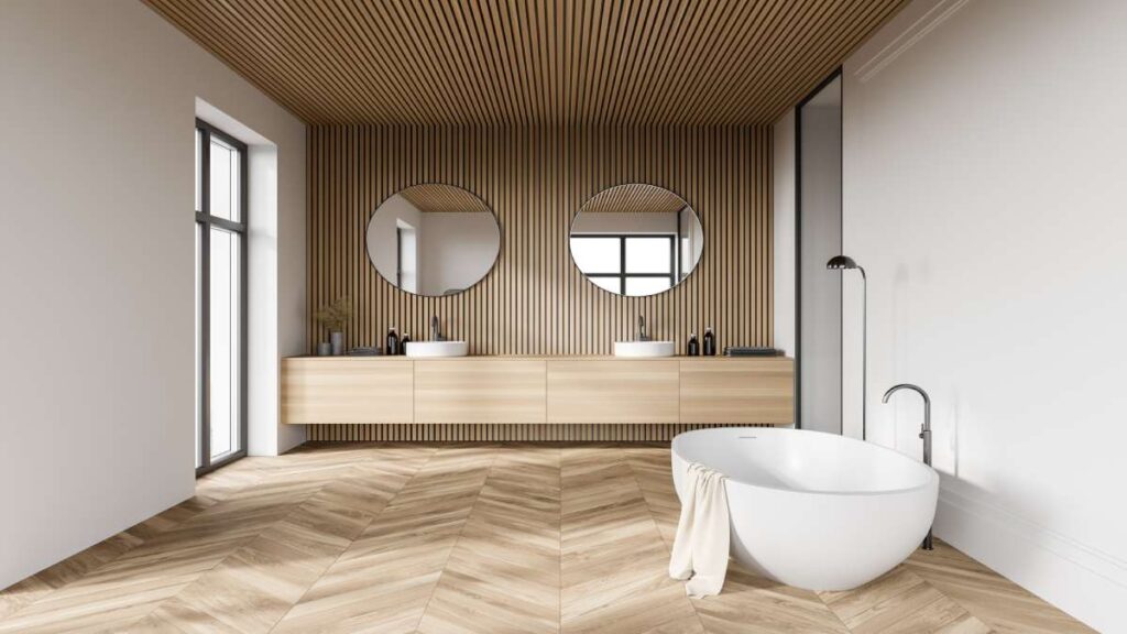 Moderne, strakke badkamer met twee lavabo's, badkuip en parketvloer.