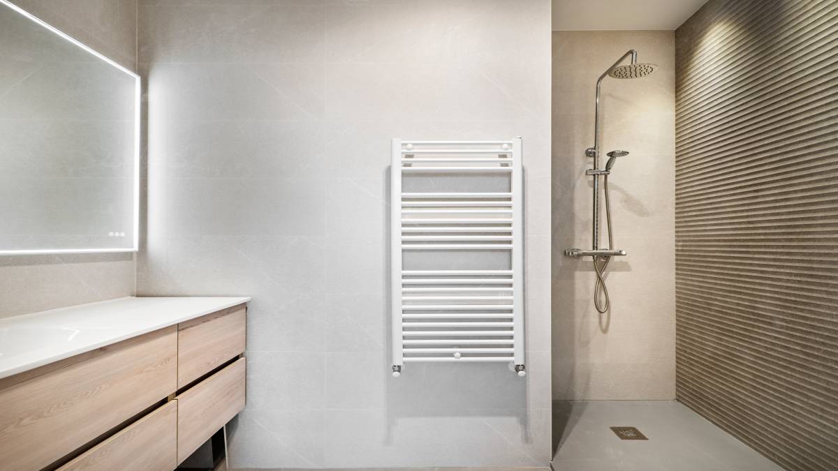 Dit is een elegante handdoekradiator die tegen de muur van een badkamer is gemonteerd.
